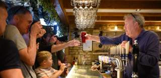 Jeremy Clarkson passes a pint to a customer at his busy bar at The Farmer's Dog