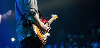 A person plays a guitar on stage at a live show