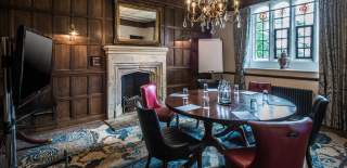 A small meeting room with wood paneled walls and chandeliers at Ellenborough Park