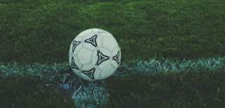 Photograph of a black and white football on a pitch