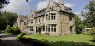The impressive Cotswold stone Hare & Hounds Hotel surrounded by landscape gardens