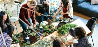 A group of people gather round a large table for a craft activity