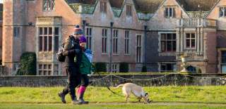 A couple walking their dog in front of Charlecote Park