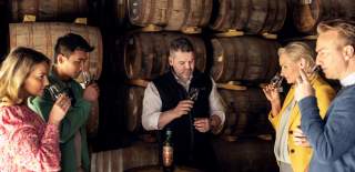 Group smelling whiskey with guide at distillery