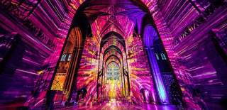 Purple and yellow light fills the interior of Tewkesbury Cathedral in the Cotswolds