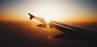 Photograph of an aeroplane wing with the sun setting behind it