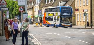 Two women laugh and chat whilst waiting for a bus in Witney