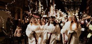 Lucia med sine terner i tog nedover gågata i Sarpsborg under julegateåpningen. Foto.