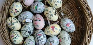 A wicker basket filled with pastel-coloured handpainted eggs from The Gloucester Guild of Craftsman