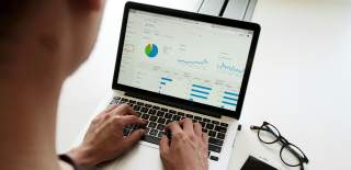 Person scrutinising data and graphs on a laptop