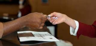 A receptionist hands over a keycard to a hotel guest