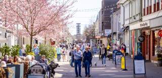 Mennesker som går i gågata og sitter på uteserveringen i Sarpsborg sentrum. Foto.