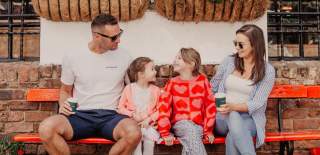 Family enjoying coffee and hot chocolate on a bench in Commercial Court Belfast