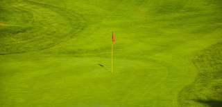 A final green at a golf course with a red flag