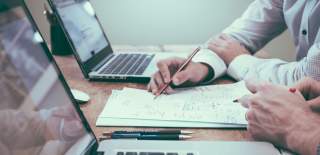 Photograph of people studying with paper and laptops