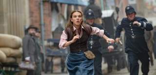A still from Enola Holmes 2, filmed on High Street in Hull. Millie Bobby Brown as Enola Holmes runs from police officers through cobbled streets.