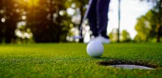 Golf ball in front of a putting hole on the golf course