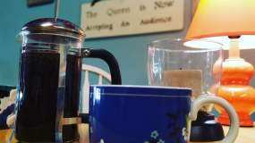 A blue mug sits next to a glass French-press at a South Press table in Knoxville.