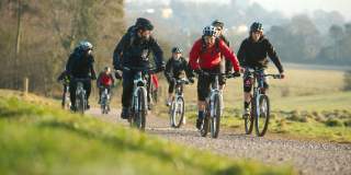 A group cycling on rented mountain bikes towards the off-road mountain biking trail at Ashton Court - credit Pedal Progression