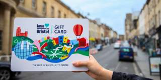 Hand holding a Love Bristol Gift Card shopping voucher in Park Street, central Bristol - credit Bristol BIDs