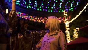 2 people dancing underneath fairylights at night