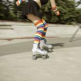 Person roller skating at a skate park wearing rainbow-striped socks.