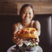 a very happy girl holding up a lobster roll at Rockfish Public House