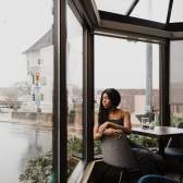 A person watching the rain fall inside a cute cafe.