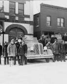 Black and White Photo of fireman standing with a fire truck in front of the old Woodstock Fire Station -currently the Woodstock Opera House.
