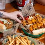 a person reaches for a fried shrimp po-boy and and french fries at Mahony's in New Orleans