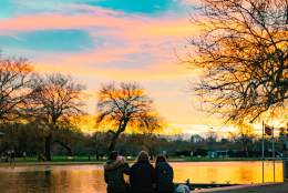 The sun sets over the River Avon as three tourist sit and watch