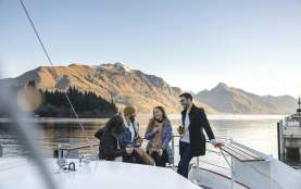 Friends sitting together at a bar on a boat with still lake and mountains in the background