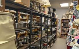 Different pots, pans, and other cookware on a shelf.