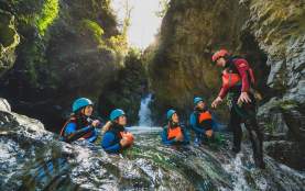 Group of people in wetsuits and helmets in the middle of a canyon