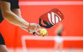 A close up of someone getting ready to serve in pickleball.