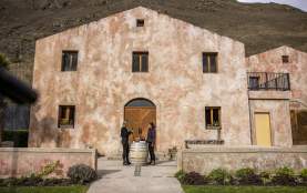 A person having a wine tasting outside Chard Farm Cellar door, a dusty pink Mediterranean style building