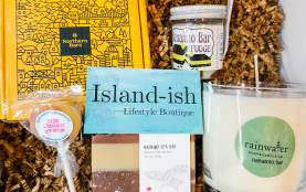 A box of goodies from Island-ish, includes a candle, soap, candy, and fragrances.