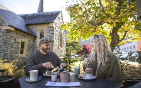 two people dining outside with a tree and church in the background