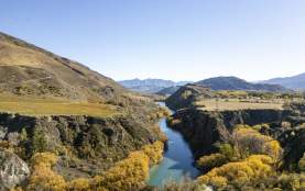 Aerial of the Kawarau River snaking through mountains and vineyards in Gibbston