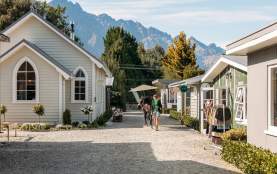 A lady walking a horse on a path lined with boutique cabins and shops