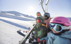Family in ski gear sitting on a chair lift at Cardrona Ski Resort