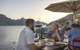 People dining by the lake with mountains in the background
