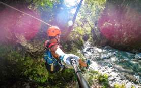 Person ziplining through a forest, over a river