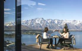 People dining outside with snow capped mountains in the background