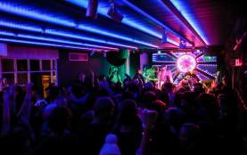 Crowd partying to live music stage with colourful lights at Yonder at night