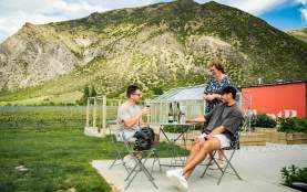 People enjoying a wine at ta table with mountains in the background