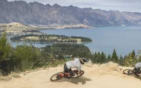 Person biking Queenstown Bike Park with view overlooking lake Whakatipu and the Remarkables mountain ranges