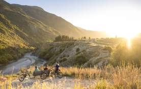 A group of cyclists taking a break next to Gibbston River