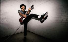 Mobley strums guitar while balancing on one foot