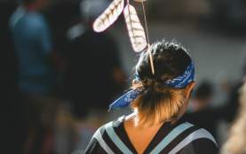 Young women with traditional Snuneymuxw regalia, picture taken from behind, woman walking away